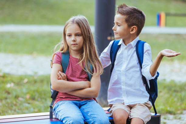Caucasian Children with Backpacks Seated Outside School