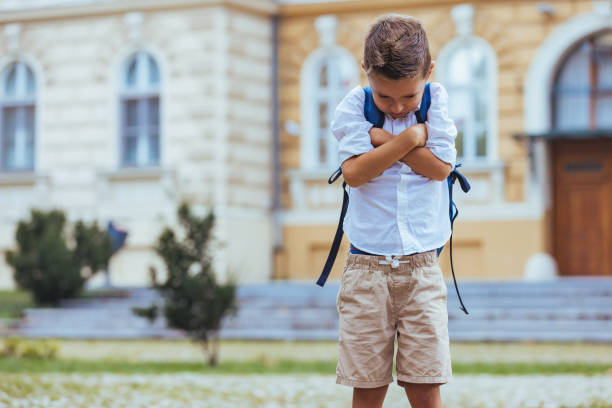 Reluctant Schoolboy with Backpack Outside Educational Building