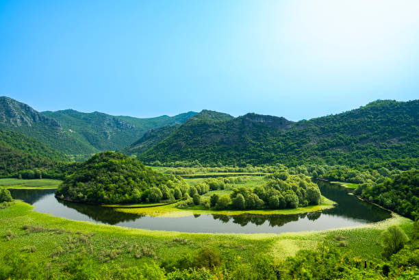 View of a serene green valley with a winding river and surrounding hills in Skadar Lake National Park, Montenegro.