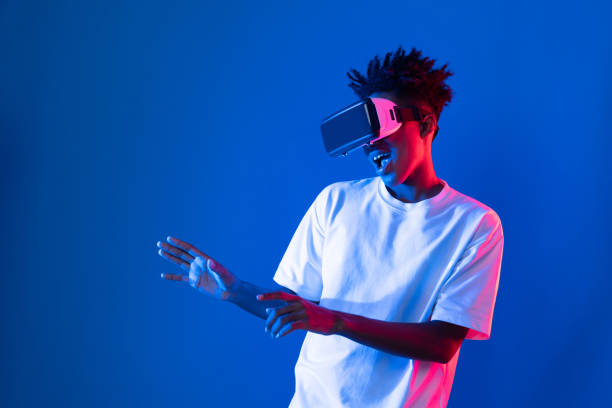 istock Young African player wearing VR point hologram 3D neon light wall. Contrivance. 2163683841