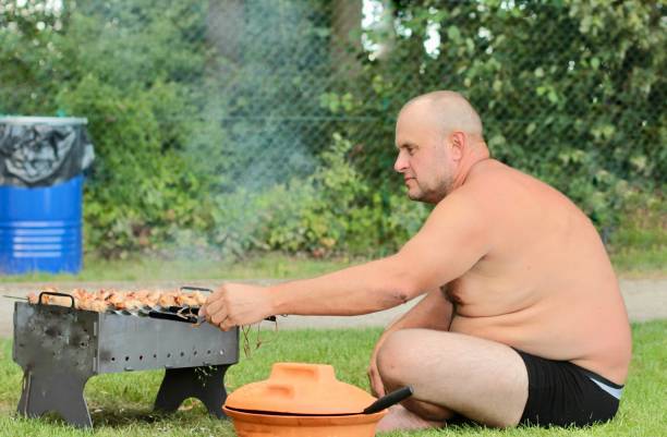 A man is grilling barbecue on the barbecue while resting on the weekend