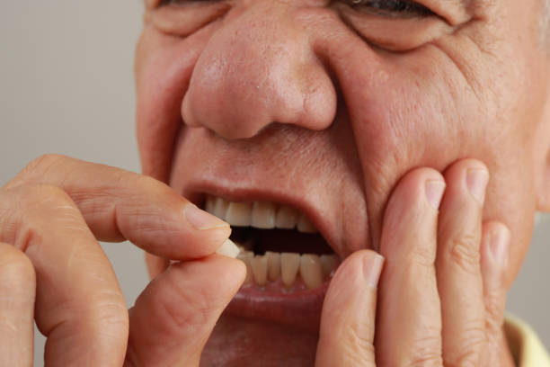 istock Man holding up his chipped tooth between his fingers. 2163685003