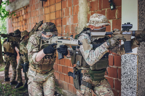 A squad of soldiers in tactical gear move strategically inside a building, demonstrating military precision, readiness and teamwork in an urban combat scenario.