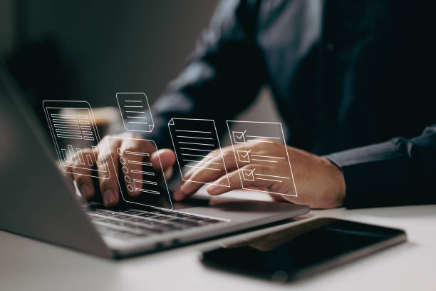 istock Typing on a laptop with digital documents and checklists floating above. It symbolizes the use of digital tools for task management, organization, and efficient workflow in a modern work environment. 2163691626
