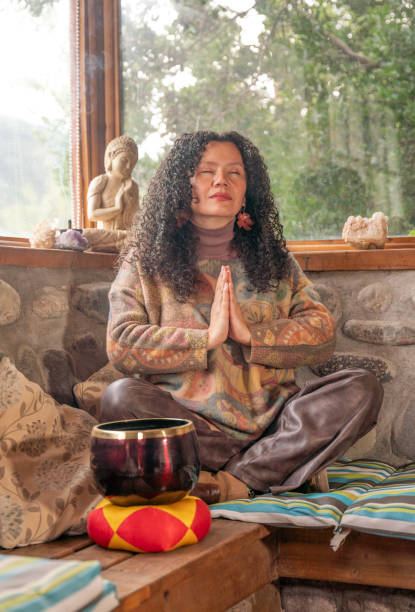 istock Woman meditating indoors with a Buddha statue 2163695506