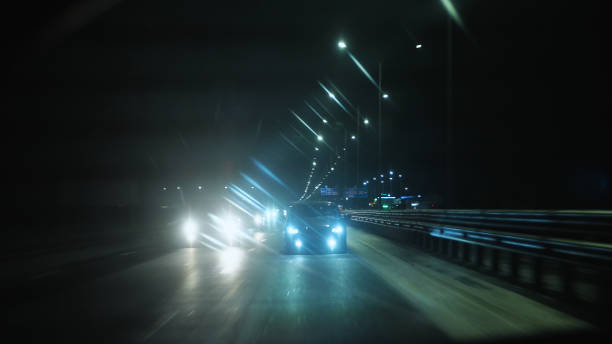 istock Cars on a night road with their headlights on 2163697914
