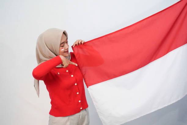 Expression of a woman in a red and white shirt holding two fists up celebrating Indonesian Independence Day, 17 August 1945