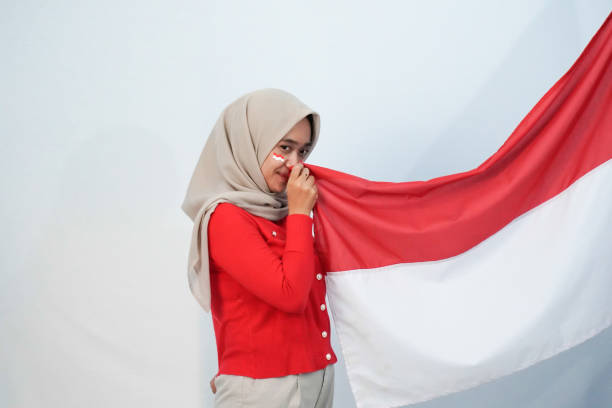 Expression of a woman in a red and white shirt holding two fists up celebrating Indonesian Independence Day, 17 August 1945