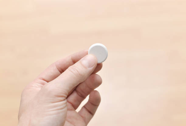 Closeup of a man's hand holding a generic collagen tablet.