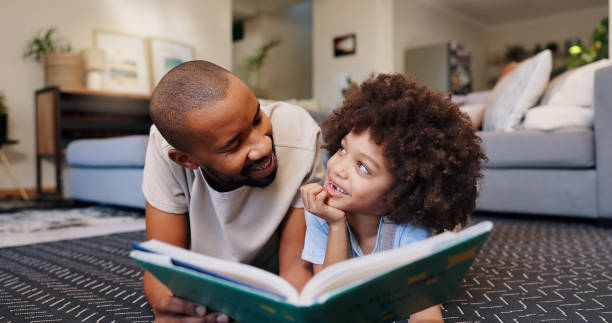 istock Reading, father and child with book on floor for education, learning or language development in living room. Love, African man and boy lying on rug for literacy, storytelling or knowledge in home 2163703226