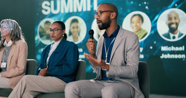 Stage, man and presenter at conference as event host, panel discussion and guest with microphone. Summit, motivational speaker and person with speech at seminar for business workshop at auditorium