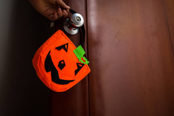 handsome man in halloween devil costume holding one lollipop on black