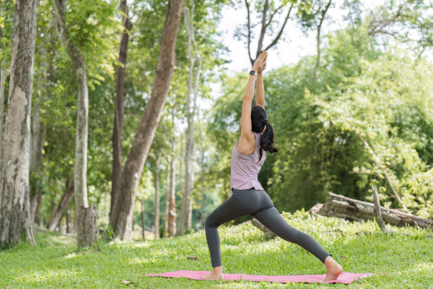 istock Young Woman Practicing Yoga in a Serene Park Setting Surrounded by Lush Greenery and Trees 2163718195