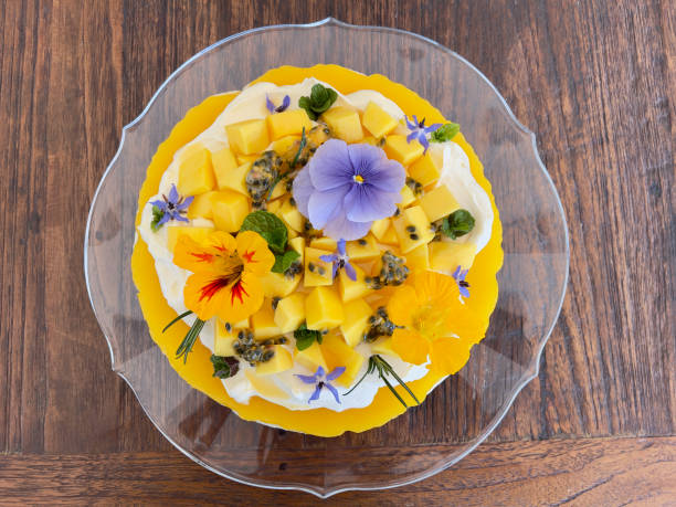 Mango cheesecake topped with cream, fresh fruit and colourful flowers