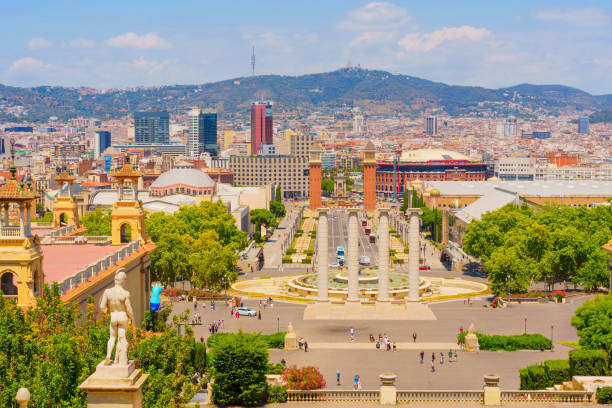 Barcelona, Spain - July 16, 2024: Elevated overlook provides stunning view of Barcelona showcasing the Four Columns, the Magic Fountain and the iconic twin towers alongside lush greenery