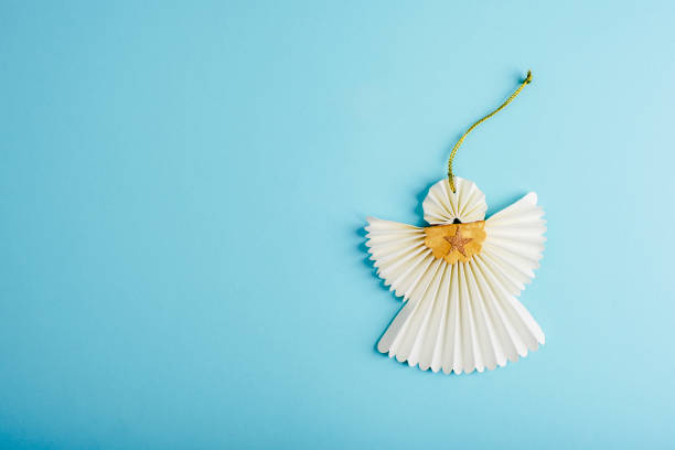 Paper angel on light blue background. Christmas concept. Top view, flat lay, copy space.