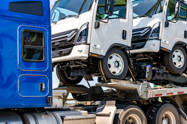 istock Classic big rig blue semi truck transporting small over cab semi trucks on the step deck semi trailer running on the road at sunny day 2163722772