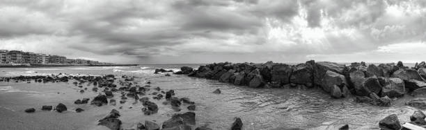 Awe bad weather in panoramic view at Rome promenade sea with dramatic sky with waves crashing at the shore and overcast rainy sky with sunbeams between suggestive and impressive clouds