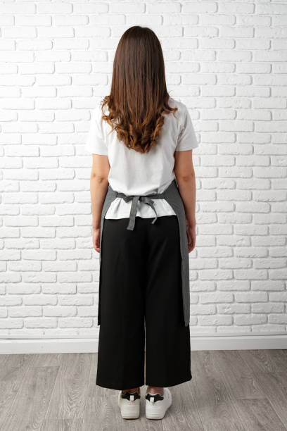 istock Back view Woman Wearing Apron in Front of a White Brick Wall 2163725471