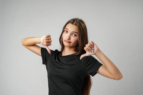 istock Young Woman Giving Thumbs Down Gesture in Studio Setting 2163726859