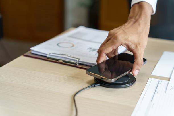 istock Charging mobile phone battery with wireless charging device in the table. Smartphone charging on a charging pad. Mobile phone near wireless charger Modern lifestyle technology concept 2163734184