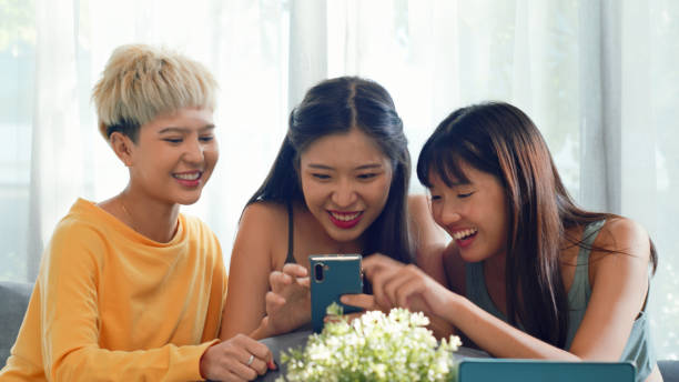 Three young women using a smartphone online shopping on the couch