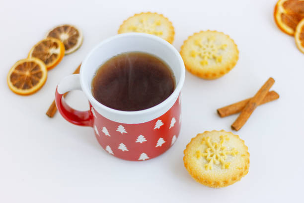 red cup, dried lemon, cinamon and mini cake with snowflake on the table