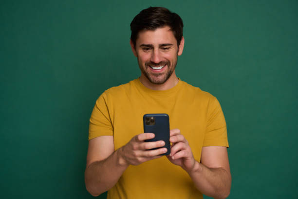 istock Happy man smiling and using smartphone on green background 2163736623