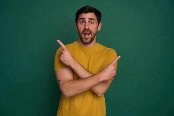 istock Excited man pointing at two sides on green background 2163736698