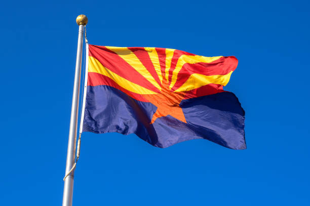 Arizona state flag waving in the wind against a cloudless blue sky