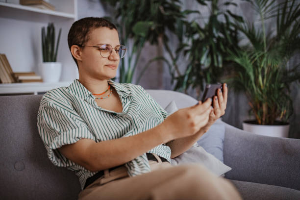 istock Person sitting on couch using smartphone with plants. 2163740058