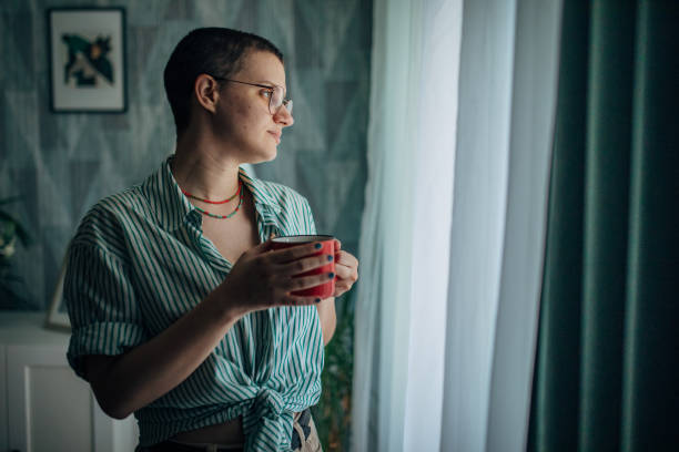 istock Person with red drink gazes out window thoughtfully. 2163740662