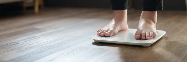 istock Woman feet standing on digital scales for diet control. 2163741433