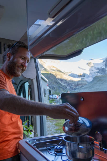 istock Man Cooking in Camper Van with Mountain View 2163741799