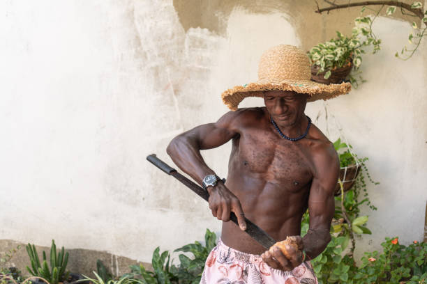 Elderly man cutting a coconut with a machete outdoors