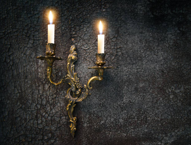 Antique wall candlestick with two burning candles on grunge shabby wall background