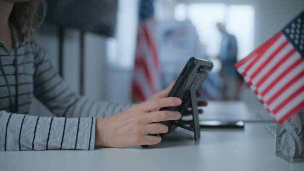 istock Female polling officer uses tablet computer and gives ballot 2163745631