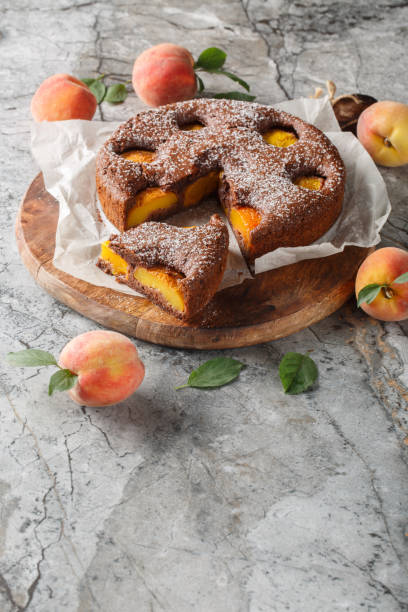 istock Chocolate fruit pie sponge cake filled with peaches close-up on wooden board. Vertical 2163745987