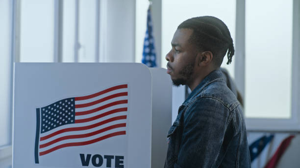 istock African American man stands and decides at voting booth 2163747162