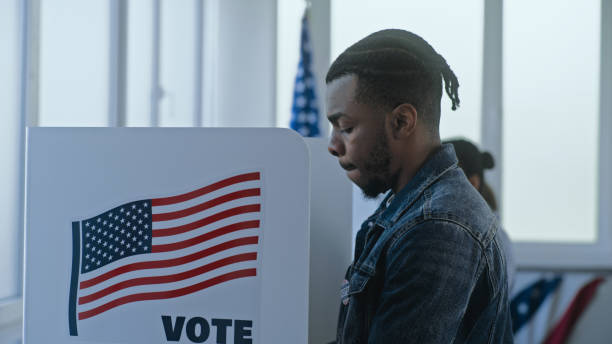 istock African American man stands and decides at voting booth 2163750239
