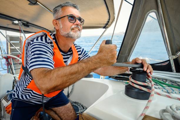istock Mature man on the sailing boat using a winch 2163752099