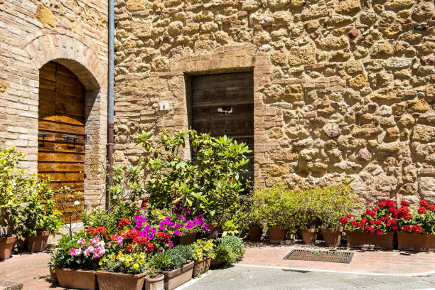 An old yard in a small Italian town. The yard is decorated with colorful flowers placed in wooden boxes.