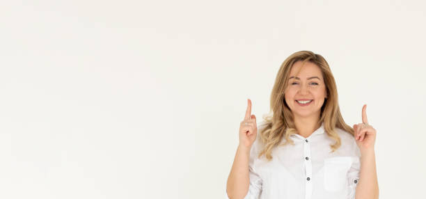 istock Smiling woman pointing finger up over white background 2163763152