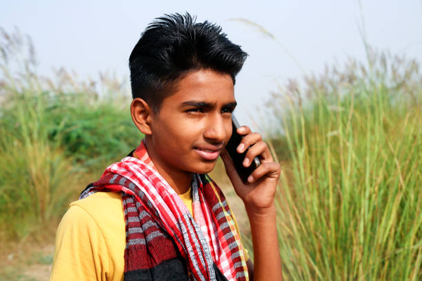 Young men of Indian ethnicity standing on country road outdoor in nature and talking on mobile phone.