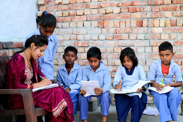 Confident village female teacher of Indian ethnicity explain information/ knowledge to the students in the class.