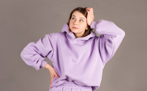 istock Beautiful female with puzzled expression, keeps hand on head, looks aside with bewilderment, poses against gray background. Body language and face expression 2163773727