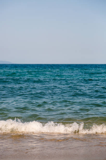 Close-up, front view of waving sea and blue bright sky as copy space at sunny summer day.
