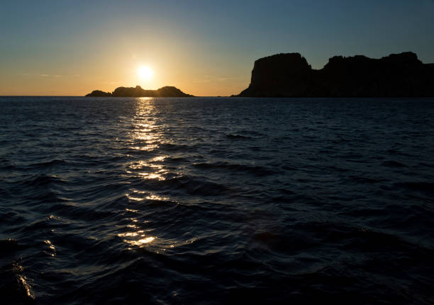 The landscape with the sunset over the sea and silhouette of island.