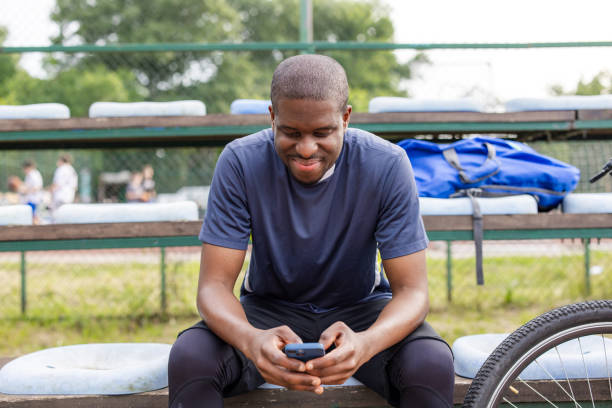 istock Man in sportswear smiling while using smart phone outdoors 2163776649