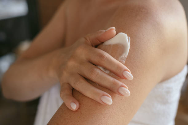 nahaufnahme weiblicher hände und ein abstrich von creme oder lotion oder serum auf der haut, frau trägt feuchtigkeitsspendende creme oder lotion nach dem duschen auf, tägliche körperpflegeroutine - auftragen stock-fotos und bilder